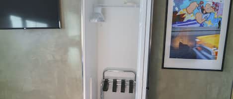 A small bathroom with a shower, a towel rack, and a framed picture on the wall.