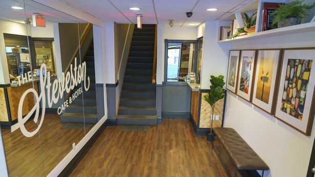 Een hotel lobby met een houten vloer, een trap en een receptiebalie.
