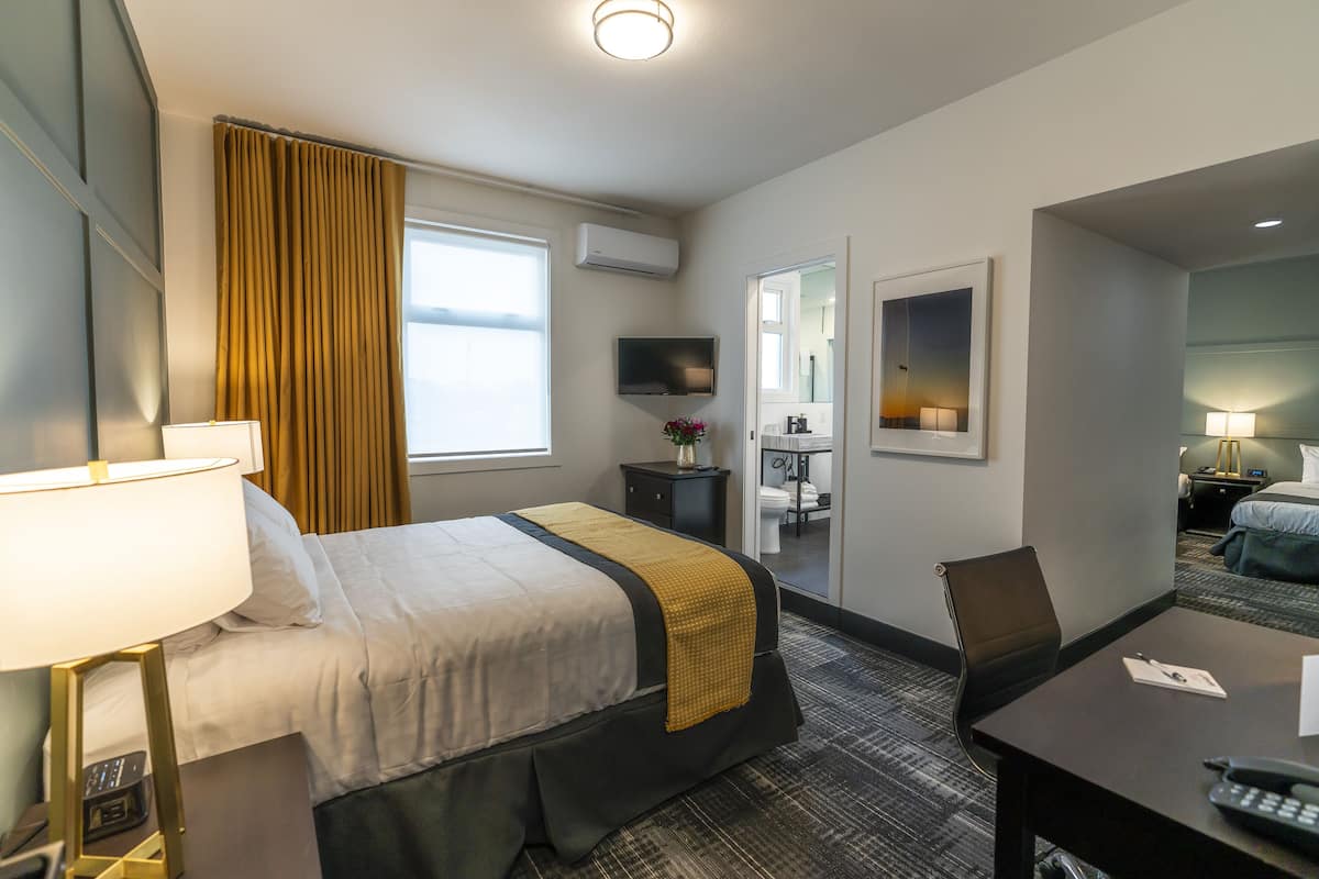 Une chambre d’hôtel équipée d’un lit, d’un bureau, d’une chaise, d’une lampe et d’un téléviseur.