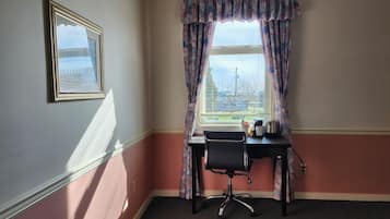 A corner room with a desk, chair, and window with curtains.