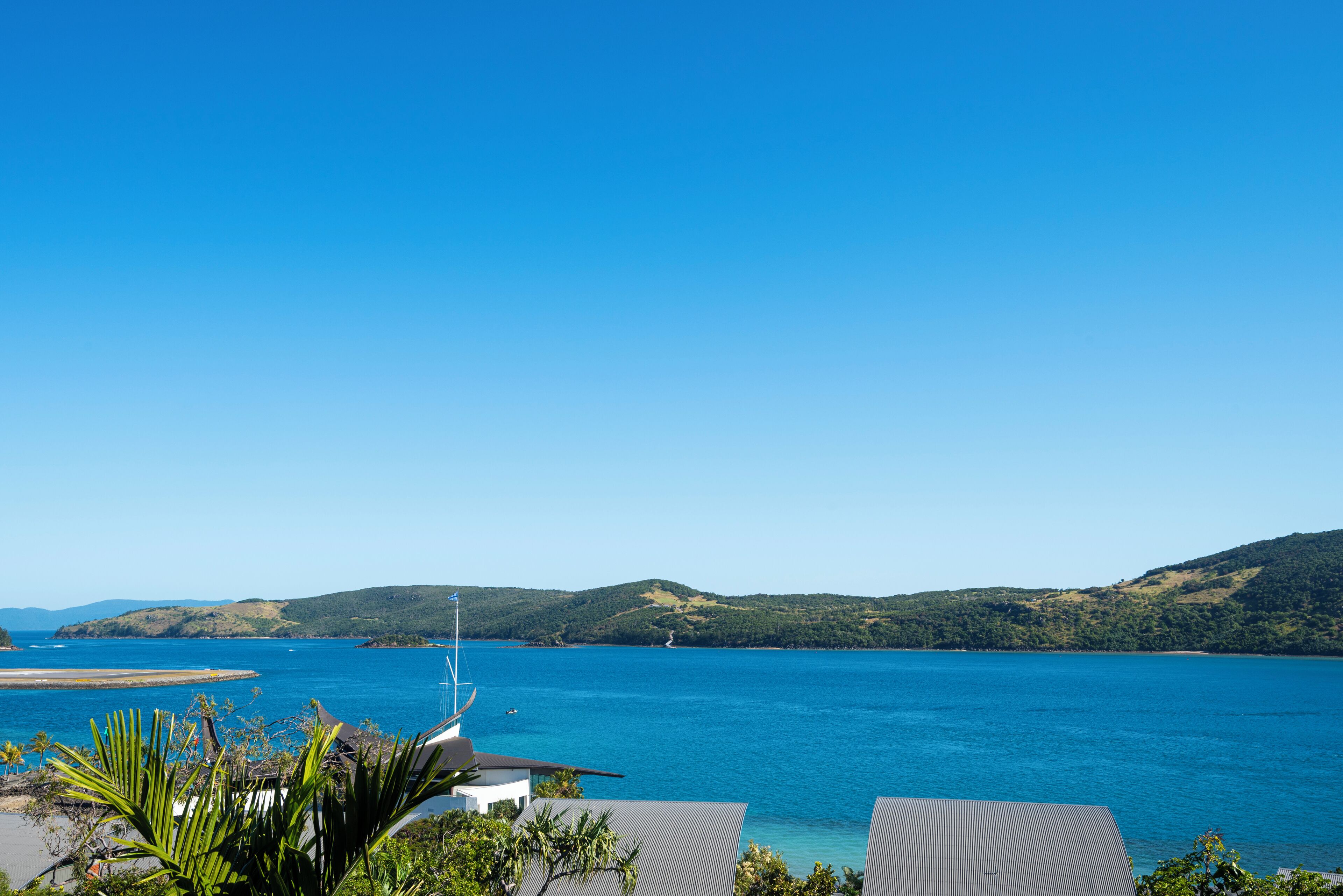 A coastal view with a clear sky, a body of water, and hills in the distance.