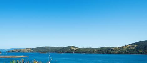 A coastal view with a clear sky, a body of water, and hills in the distance.