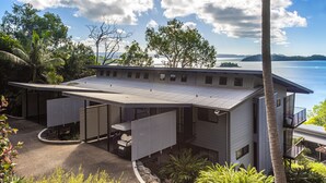A modern house with a covered patio, a swimming pool, and a view of the sea. - Panorama 3 Hamilton Island 2 Bedroom Ocean View Near Marina With Golf Buggy (Whitsundays)