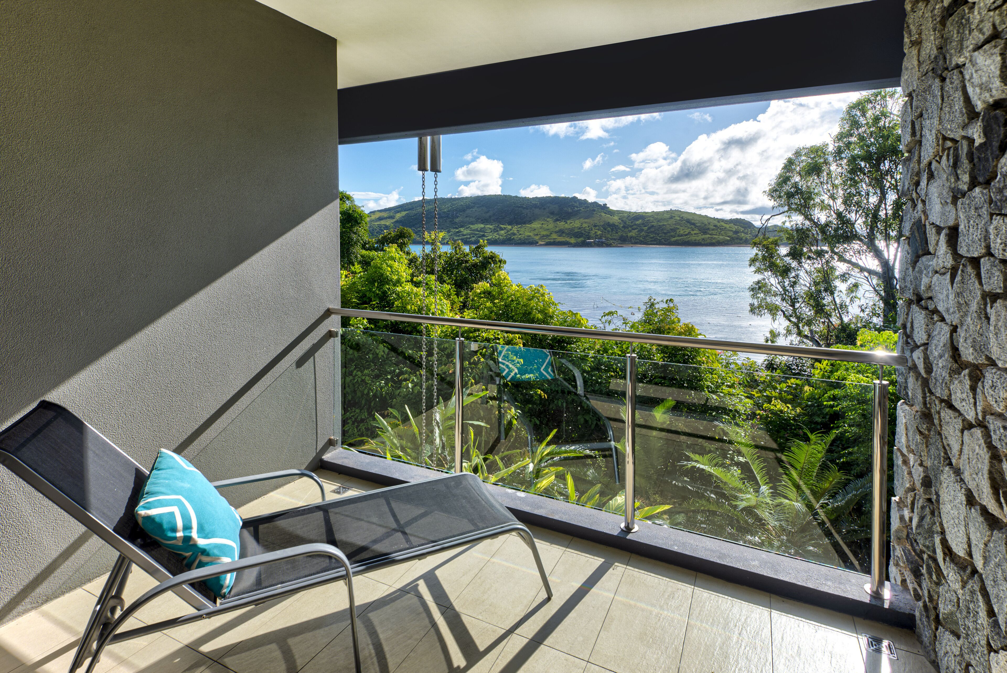 A balcony with a chair and a view of a lake and mountains.