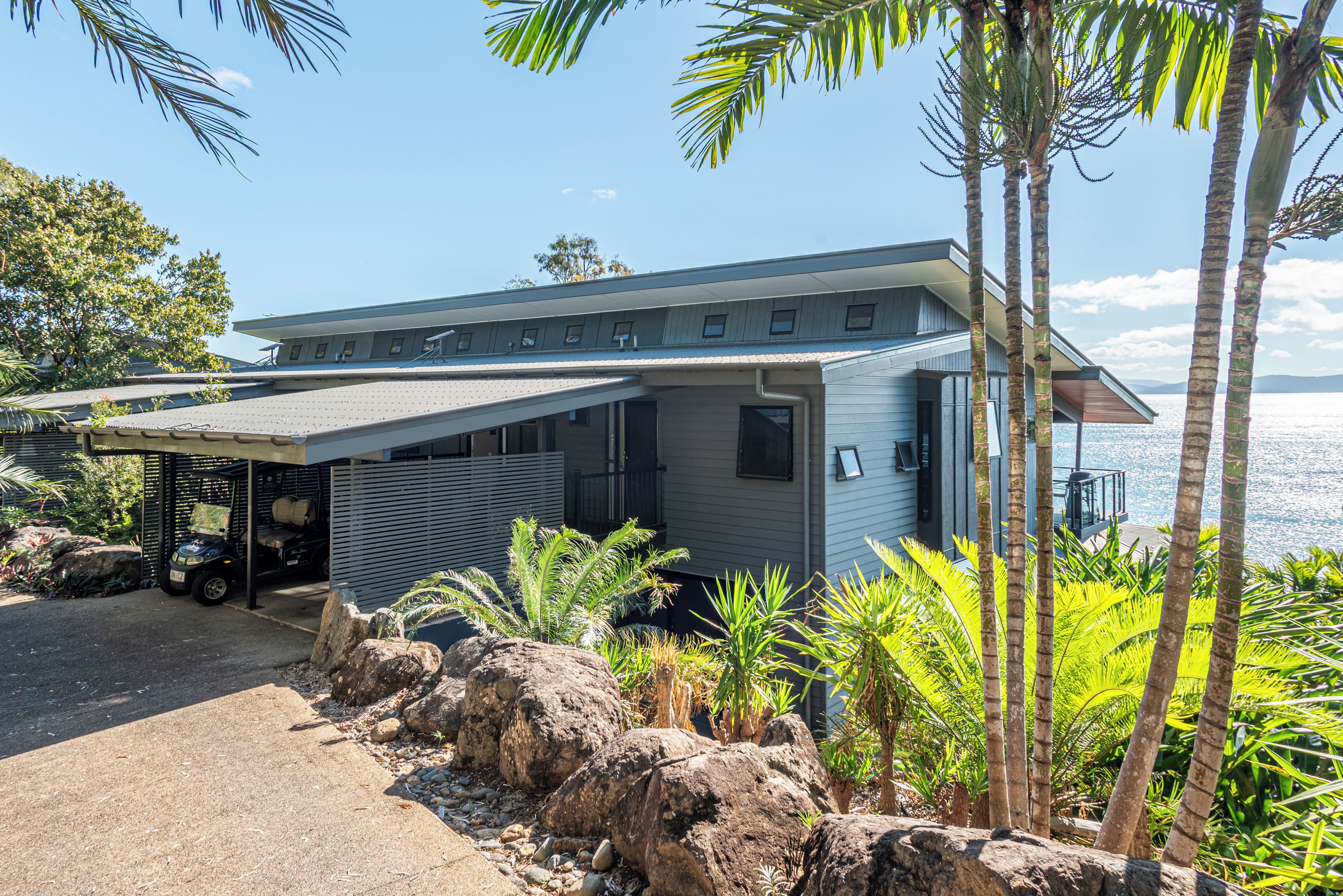 Une maison moderne dotée d’un porche abrité, d’un garage et offrant une vue sur la mer.