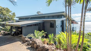 A modern house with a covered porch, a garage, and a view of the sea.