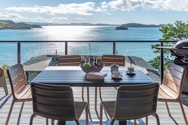 A dining area with a table and chairs overlooking a body of water. - Shorelines 27 Hamilton Island 2 Bedroom Ocean View Near Marina With Golf Buggy (Whitsundays)