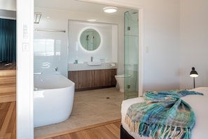 A modern bathroom with a freestanding bathtub, a glass-enclosed shower, and a vanity with a mirror. - Shorelines 27 Hamilton Island 2 Bedroom Ocean View Near Marina With Golf Buggy (Whitsundays)