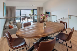 A modern dining area with a wooden table, leather chairs, and a vase of flowers.