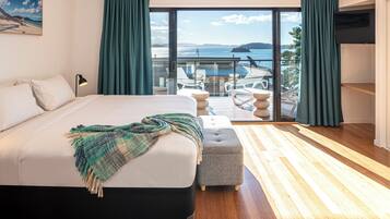 A bedroom with a large bed, a view of the sea, and a balcony with outdoor furniture.
