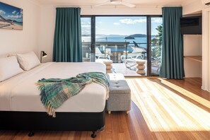 A bedroom with a large bed, a view of the sea, and a balcony with outdoor furniture. - Shorelines 27 Hamilton Island 2 Bedroom Ocean View Near Marina With Golf Buggy (Whitsundays)