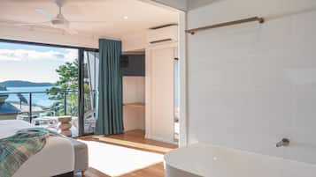 Un dormitorio moderno con un gran ventanal, una cama, una bañera y un ventilador de techo.