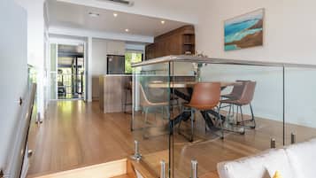 A modern kitchen with a glass dining area, wooden flooring, and a view of the outdoors.