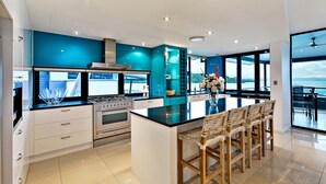 A modern kitchen with a central island, stainless steel appliances, and a view to the outside. - Villa 12 The Edge Oceanfront Deluxe 3 Bedroom Near Marina With Golf Buggy (Whitsundays)