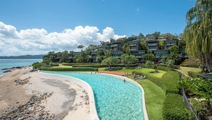 A resort with a swimming pool, beach, and lush landscaping.