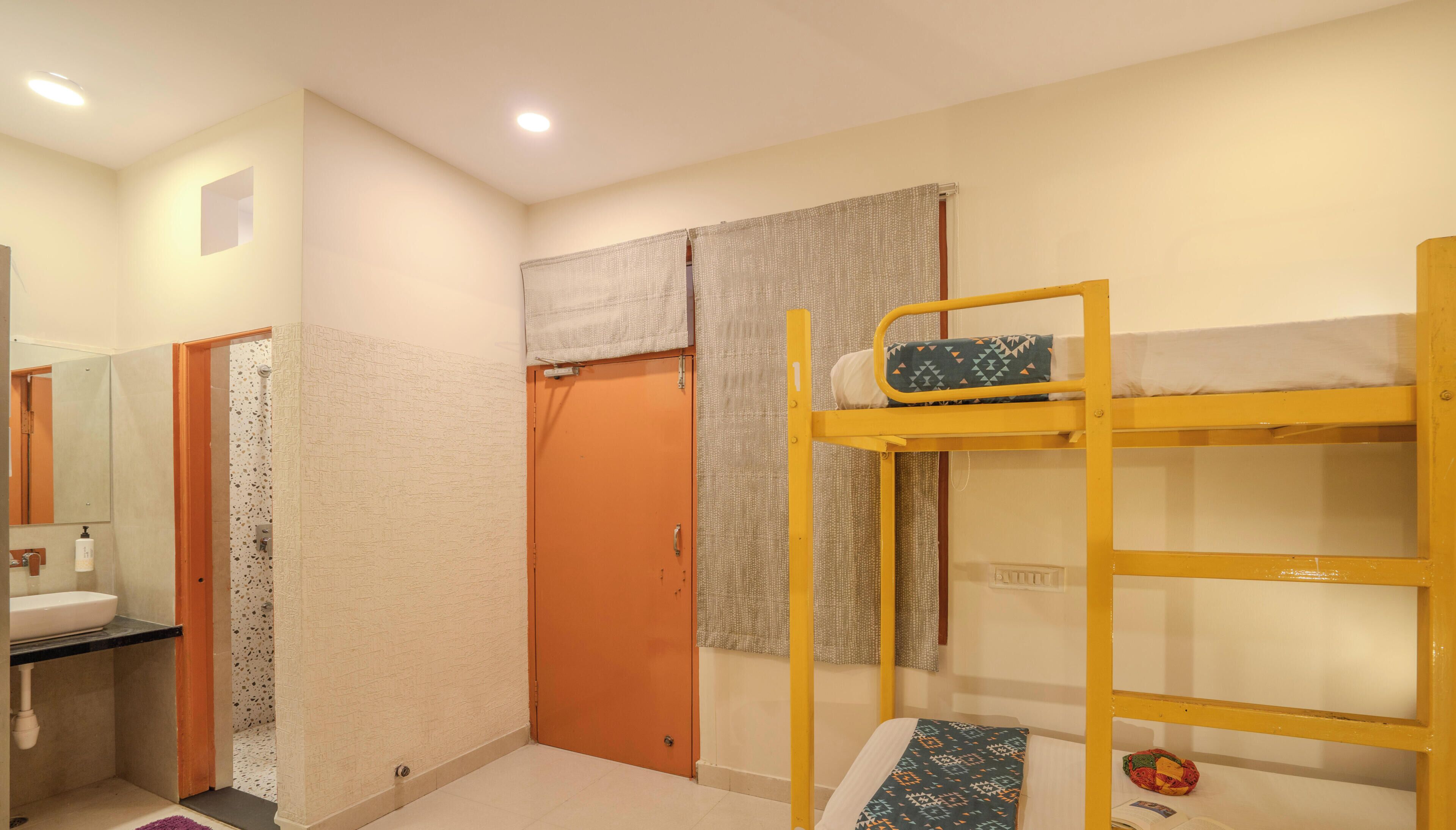 Una habitación con literas, un baño con lavamanos y una puerta que da a otra habitación.