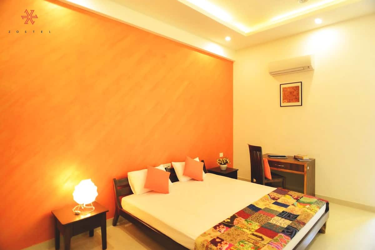 Una habitación de hotel con una cama grande, un escritorio y una mesita de noche.