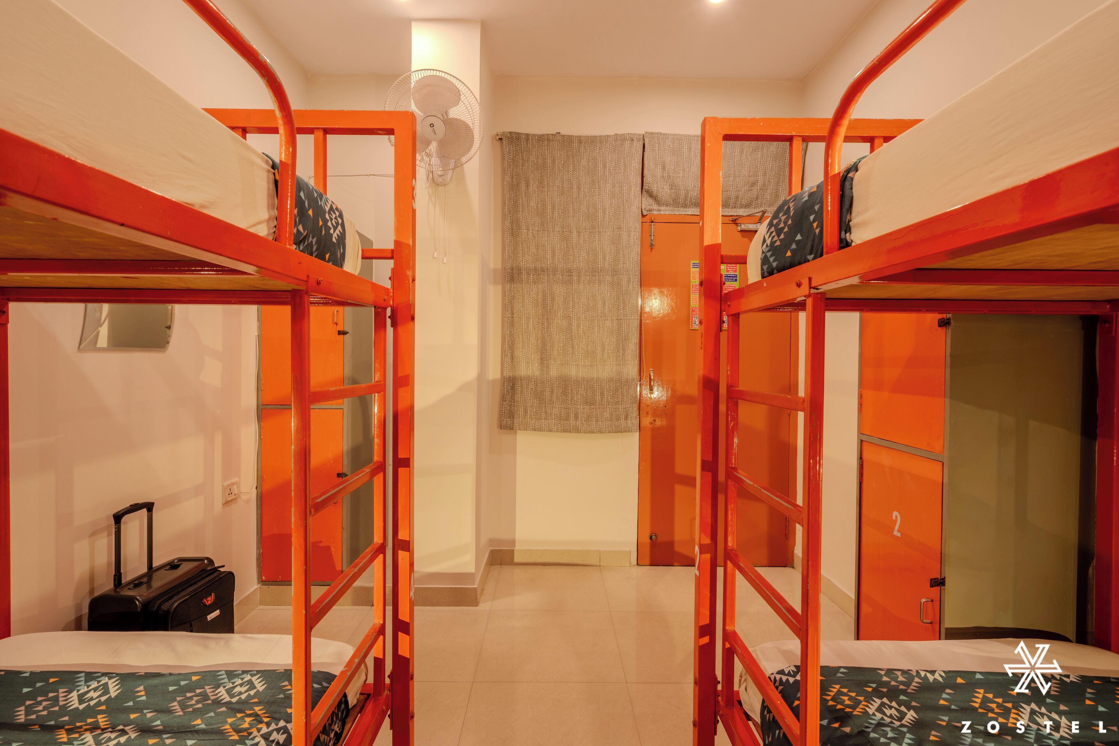 Un dormitorio con literas, una maleta y un ventilador.