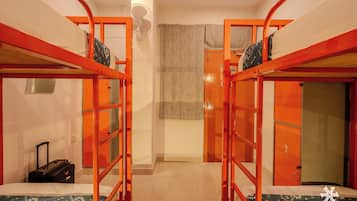 Un dormitorio con literas, una maleta y un ventilador.