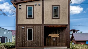 A two-story building with a wooden facade and a small porch. - Cocoa Niseko (Kutchan)
