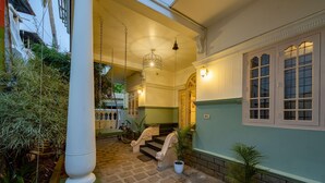 A covered outdoor area with a staircase leading to a building entrance, surrounded by potted plants and a bicycle. - Zostel Kochi (Fort Kochi) (Kochi)