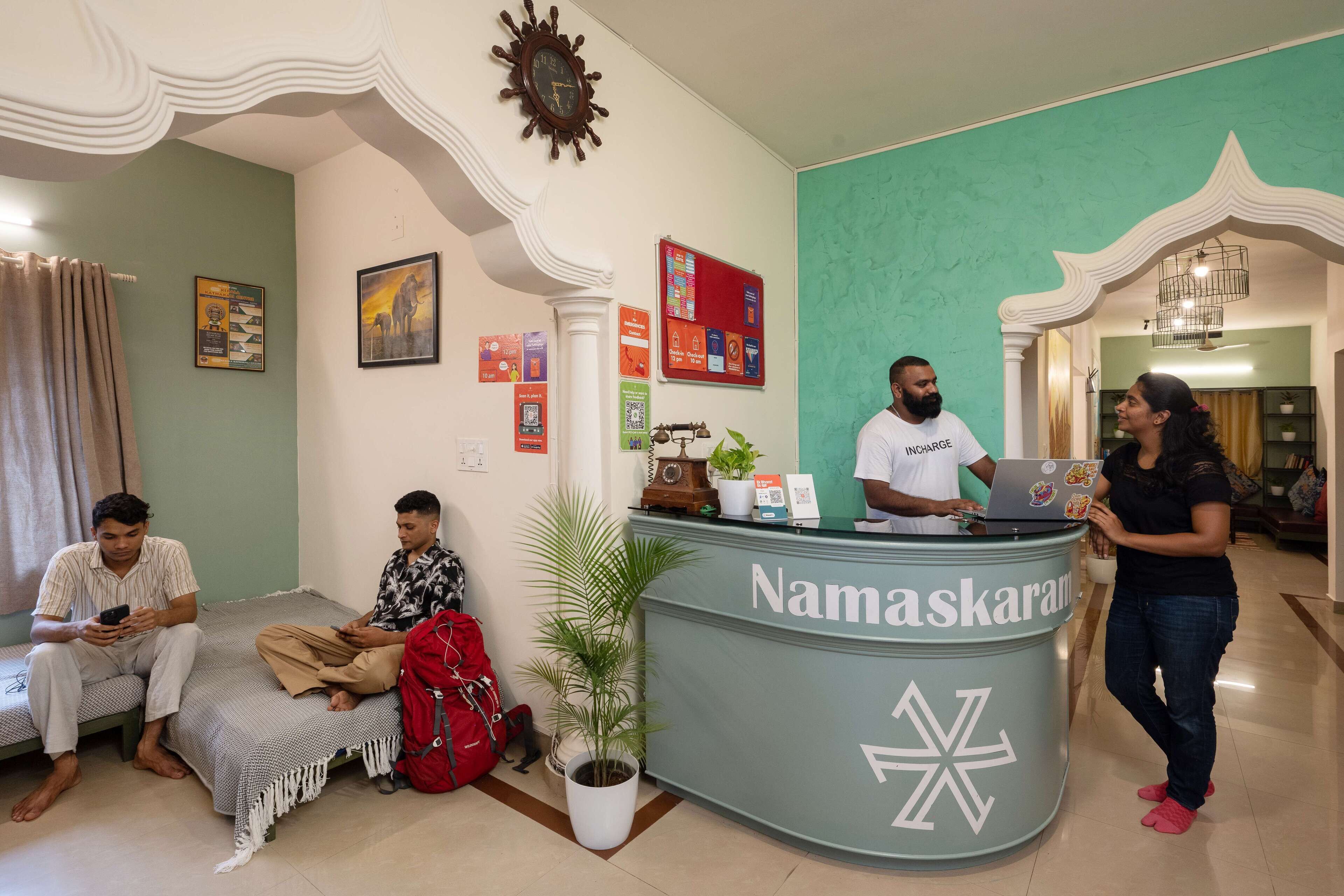 A reception area with a reception desk labeled "Namaskaram" and a clock on the wall.