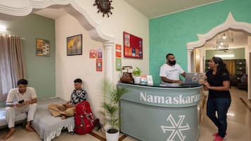 A reception area with a reception desk labeled "Namaskaram" and a clock on the wall.