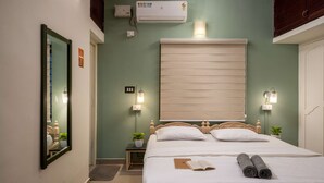 A bedroom with a bed, bedside tables, a mirror, an air conditioner, and wall-mounted lights. - Zostel Kochi (Fort Kochi) (Kochi)