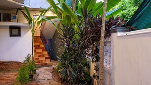A courtyard with a staircase, potted plants, and a white wall. - Zostel Kochi (Fort Kochi) (Kochi)