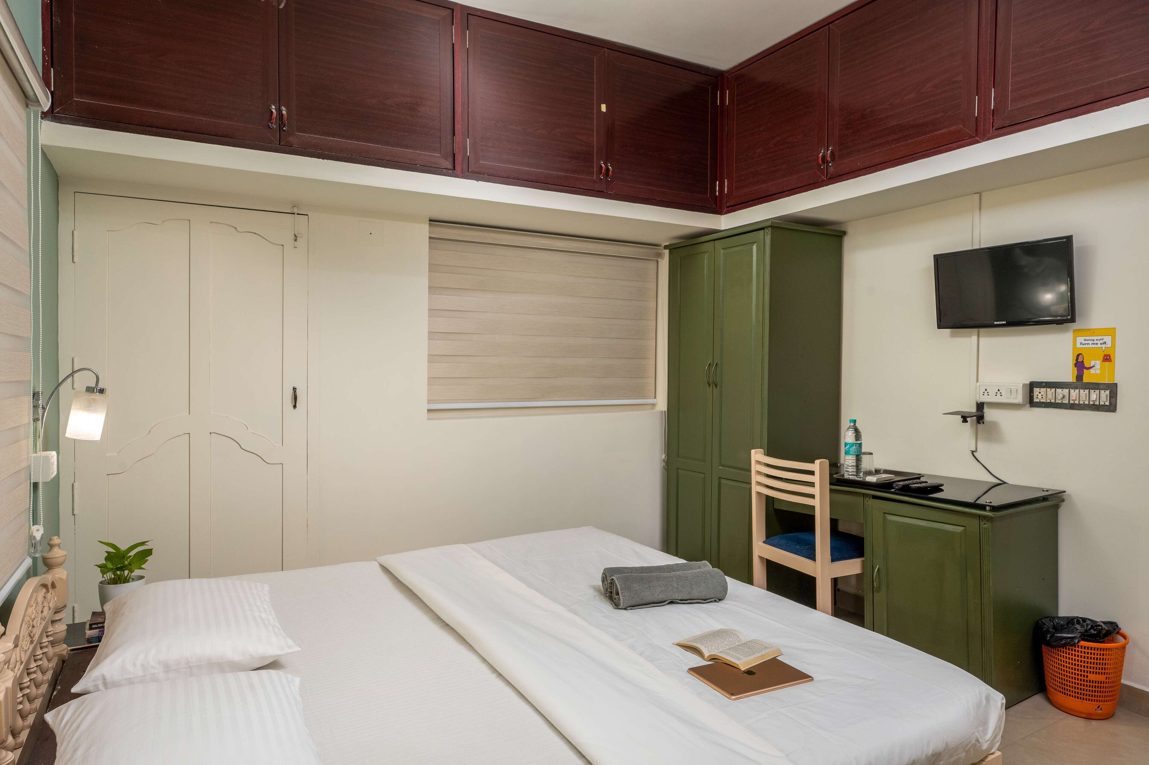 Un dormitorio ordenado con una cama, un escritorio, una silla y un televisor.