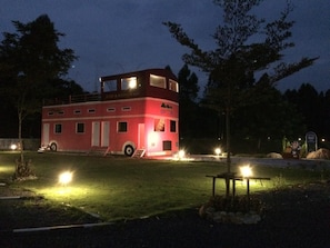 A red building with a flat roof and a balcony, surrounded by trees and a grassy area. - River & Mountain resort (Nakhon Nayok)