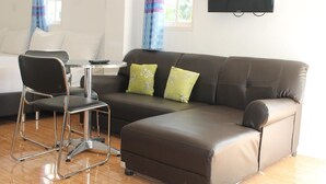 A modern living room with a brown leather sofa, a green and white patterned pillow, a black chair, and a small round table.