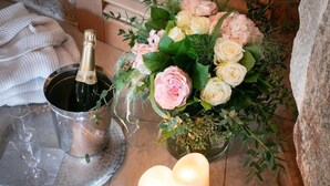 A cozy corner with a metal bucket containing a bottle, a glass, and a candle holder with lit candles. - La Vinotière (Le Conquet)
