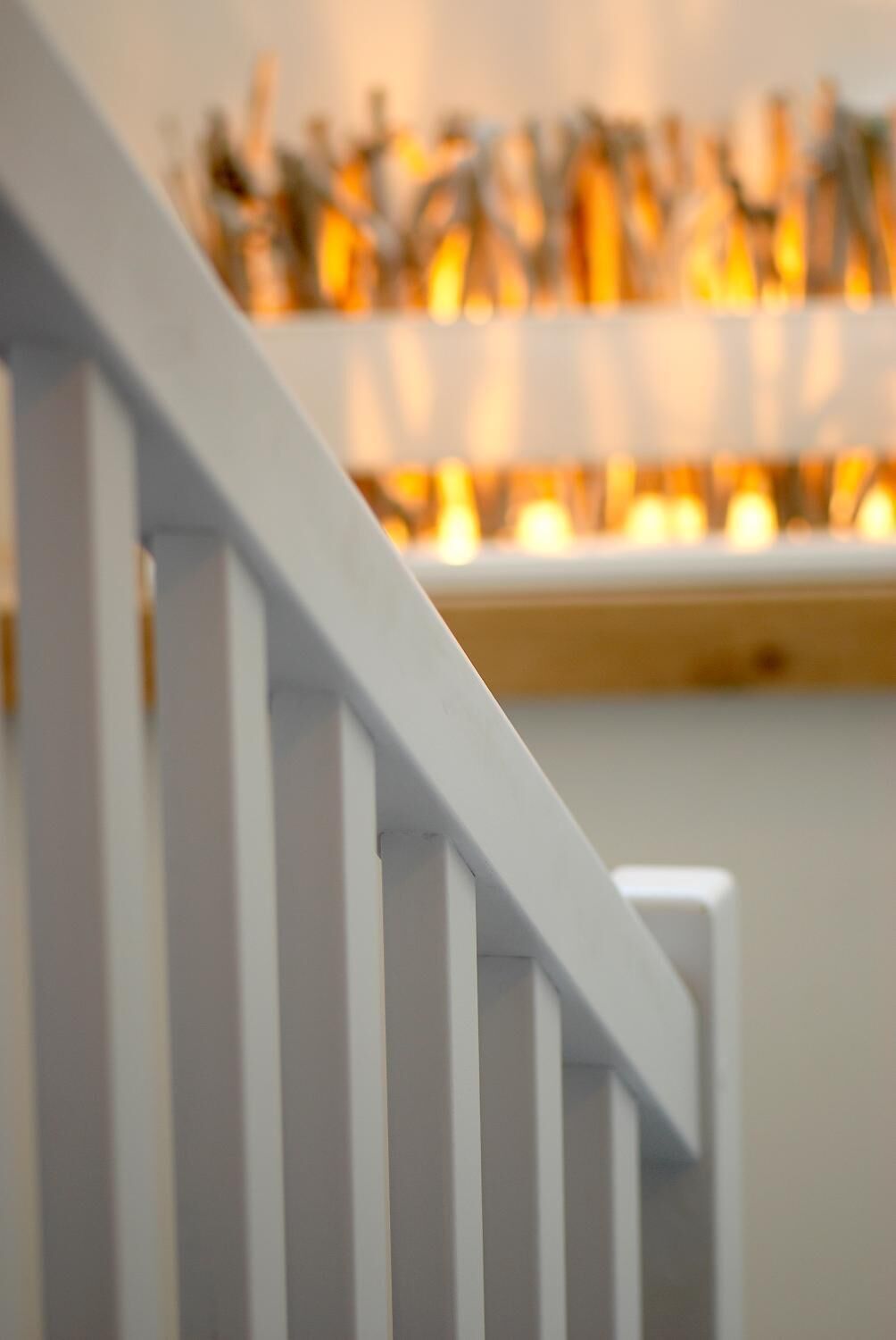 Un escalier blanc avec une rampe menant à une plateforme où est disposée une rangée de bougies.