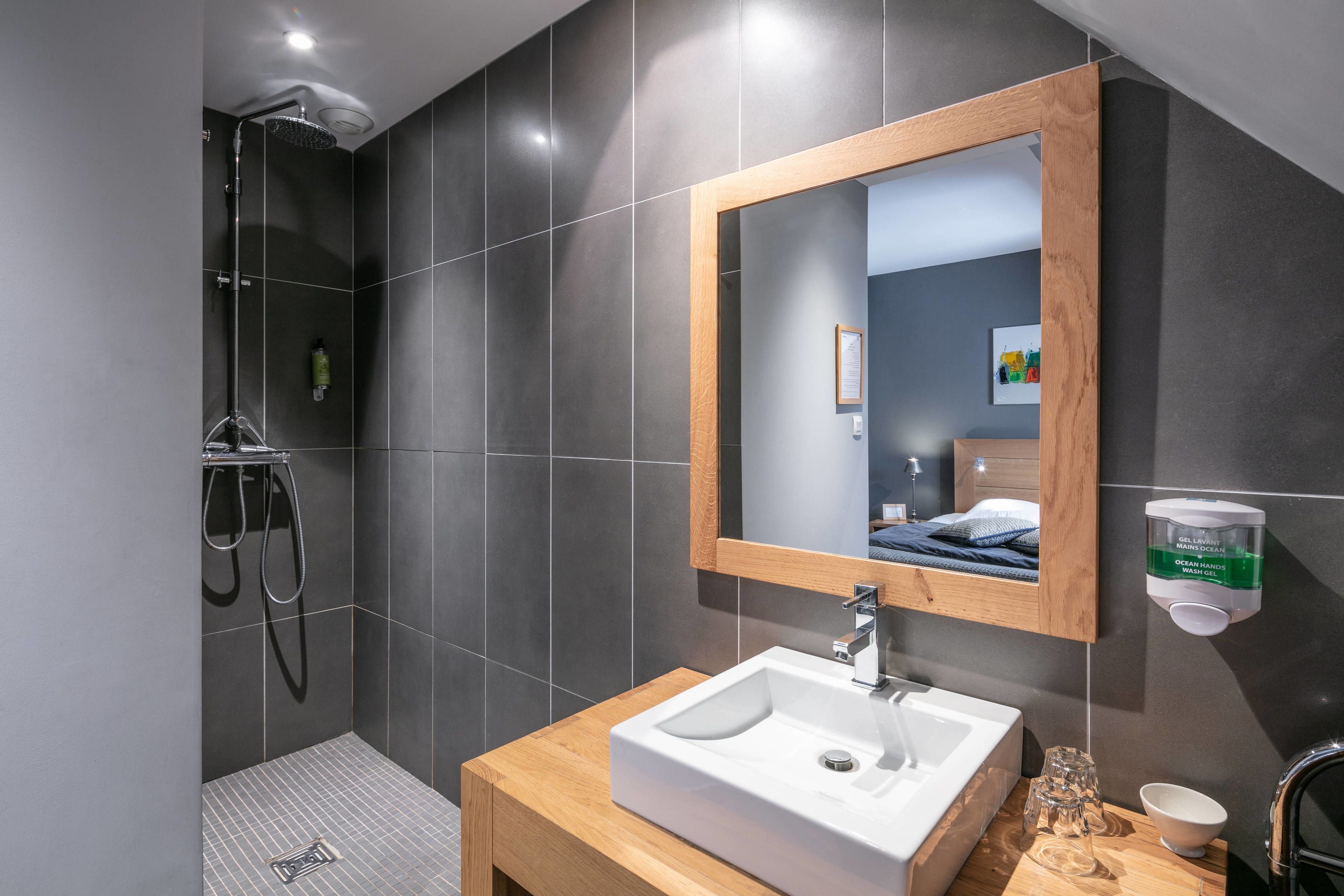 A modern bathroom with a shower, a sink, and a mirror.