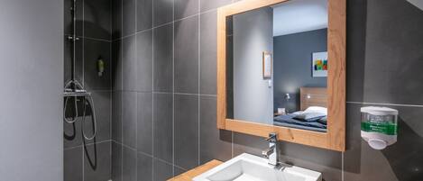 A modern bathroom with a shower, a sink, and a mirror.