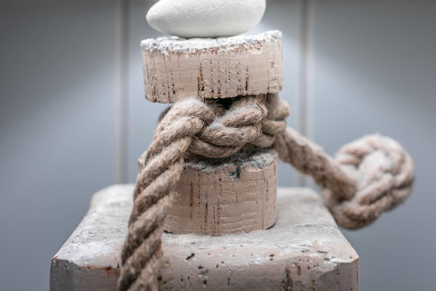 A stack of cylindrical objects with a rope tied around them, placed on a rectangular base.