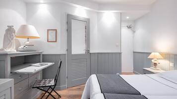 Un dormitorio con cama, escritorio con lámpara, una silla y un armario.