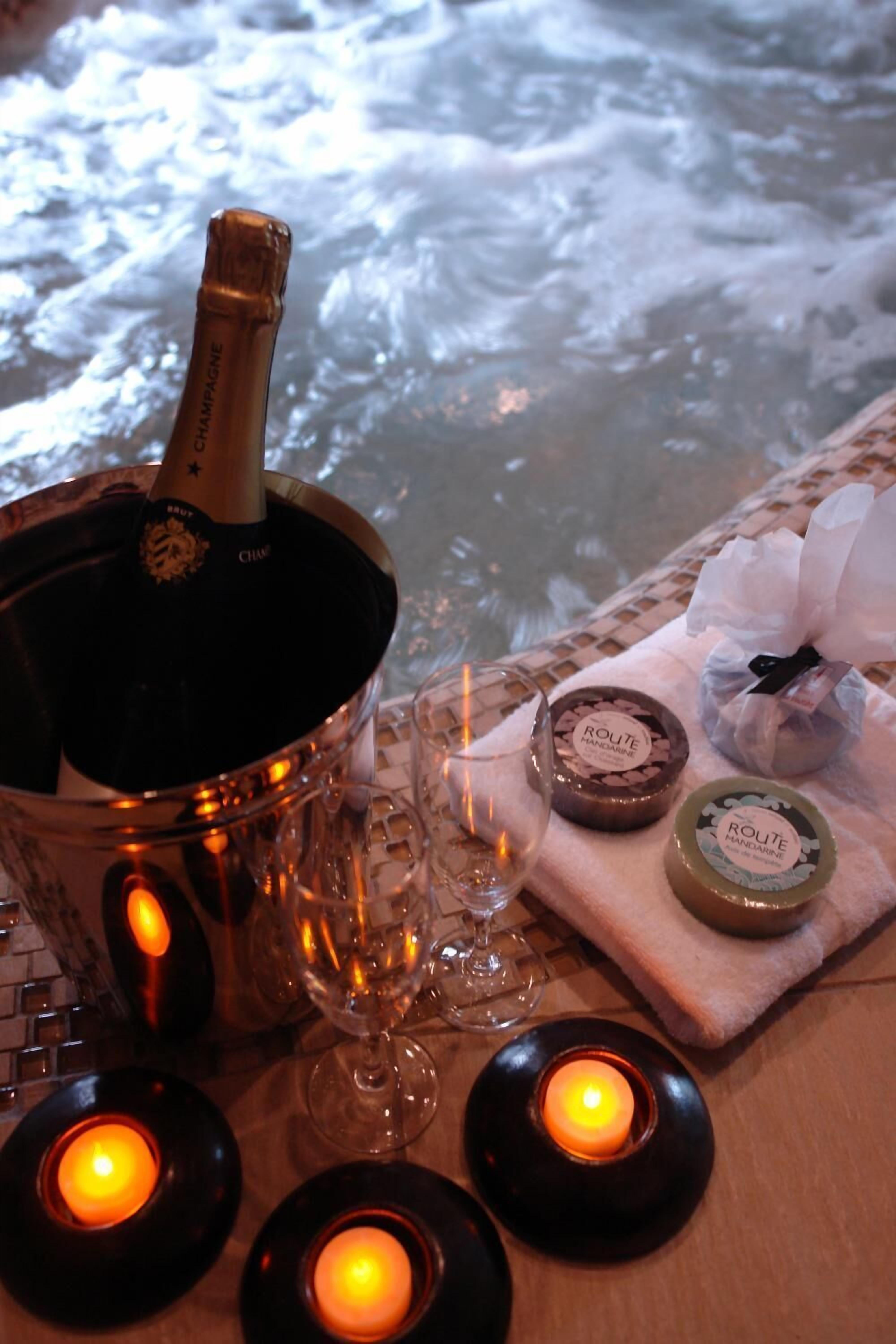 Una botella de champán en un balde, velas y pequeños recipientes con etiquetas sobre una mesa.