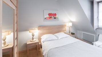 Un dormitorio ordenado con tablero de madera, mesita de noche con lámpara, teléfono en la mesita y un cuadro enmarcado en la pared.