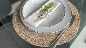 Een eettafel gedekt met borden, bestek en een middelpunt.