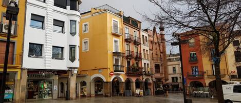 A wet plaza with historic buildings, a pharmacy, and a restaurant.
