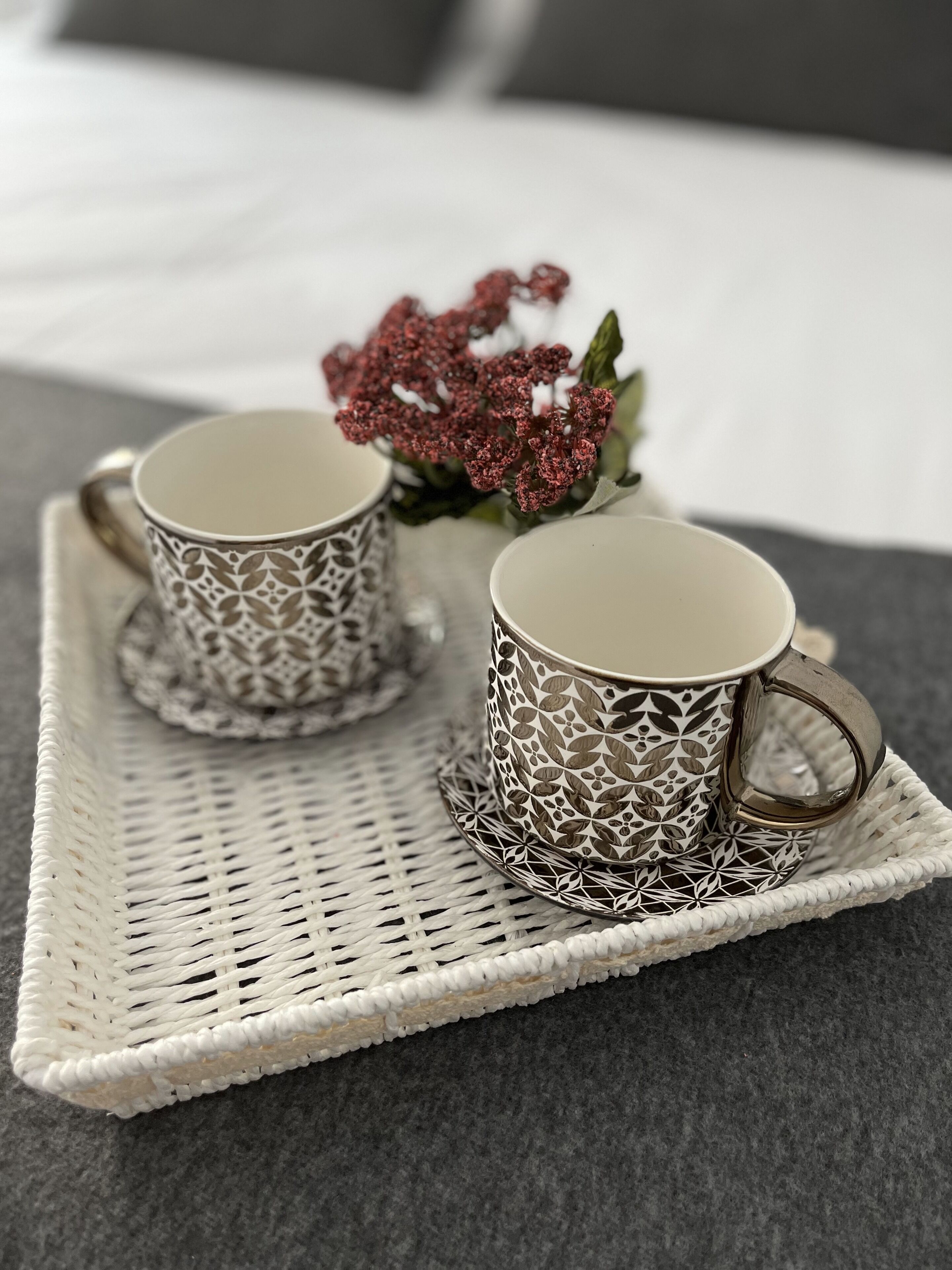 Dos tazas estampadas sobre una bandeja tejida.
