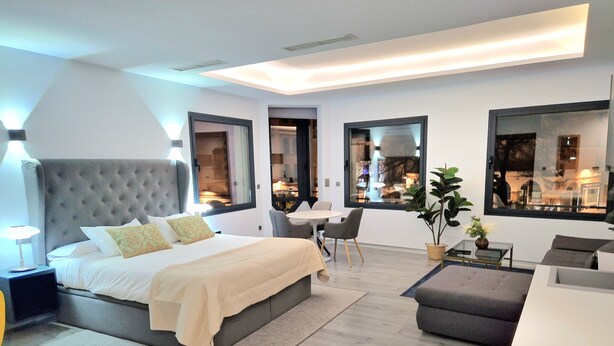 Een moderne slaapkamer met een groot bed, een bureau en een zithoek.