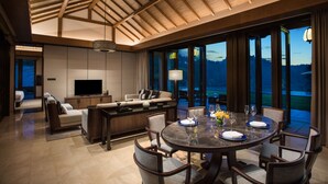 A modern dining area with a round table, chairs, and a view of a lake at dusk. - Banyan Tree Anji (Huzhou)