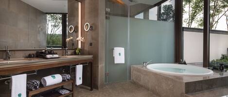 A modern bathroom with a large mirror, a bathtub, and a shower area.