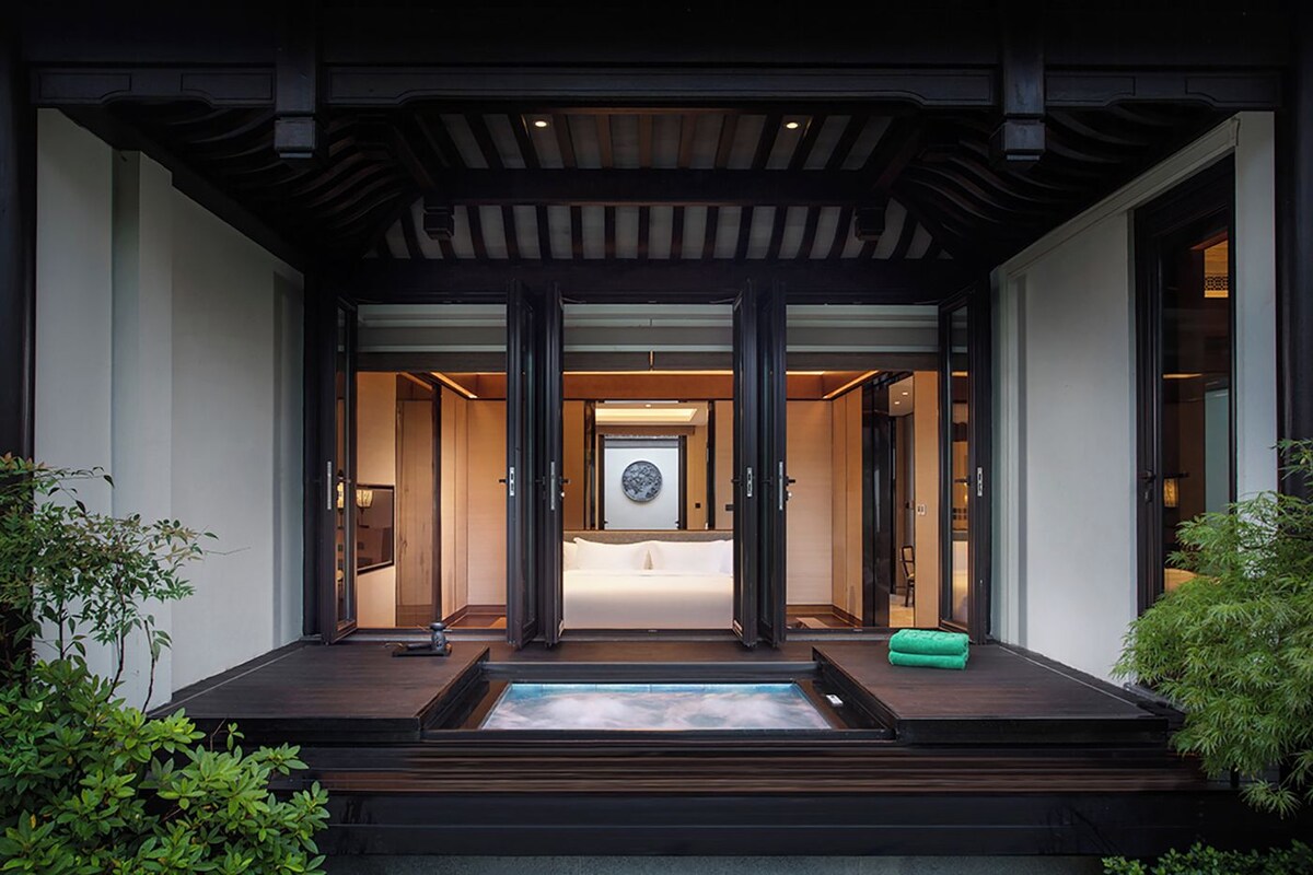 Entrada de hotel con una decoración tradicional japonesa, una recepción y vista del interior a través de las puertas.