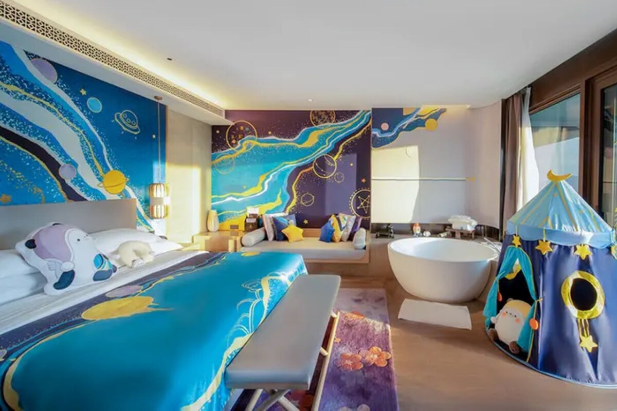 Un dormitorio con una cama grande, una bañera y una estructura tipo tienda con vistas al cielo.