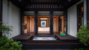 A modern building entrance with a wooden deck, a water feature, and a framed artwork above the door. - Banyan Tree Anji (Huzhou)