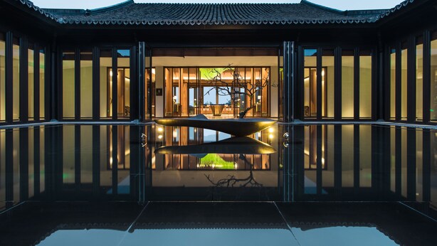 A traditional building with a reflective pool in front, large windows, and a tree in the center. - Banyan Tree Anji (Huzhou)